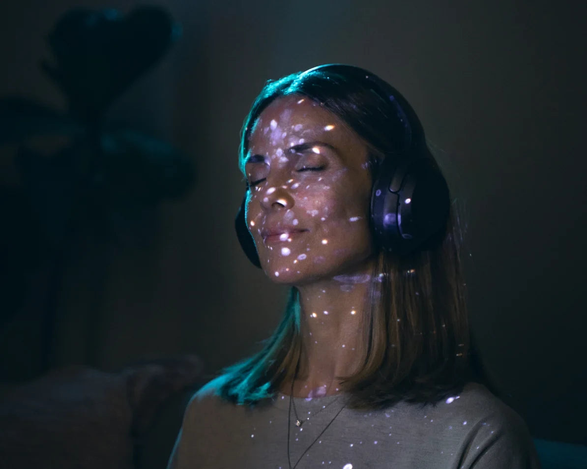 Light speckles projected across a persons face during a Lumenate session