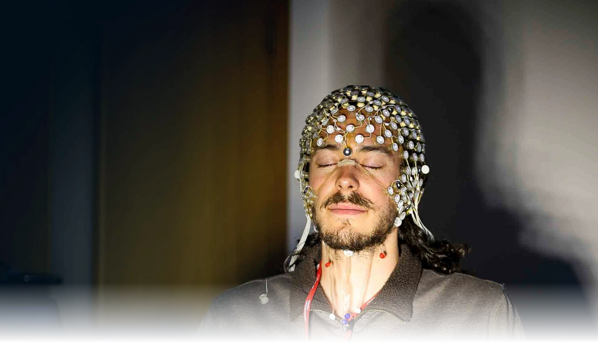 Research participant wearing an EEG electrode cap with eyes closed during a Lumenate light-stimulation session